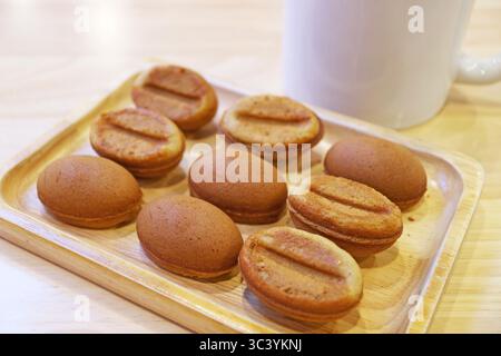 File di deliziose mini torte a forma di chicco di caffè fatte in casa su una lavagna di legno Foto Stock