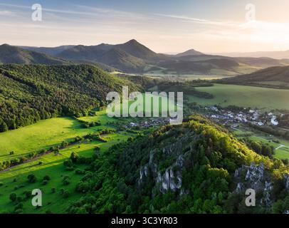 Tranquillo paesaggio con il villaggio rurale. verdi prati lussureggianti, case tradizionali e pittoresche montagne alpine sotto un blu chiaro sk Foto Stock