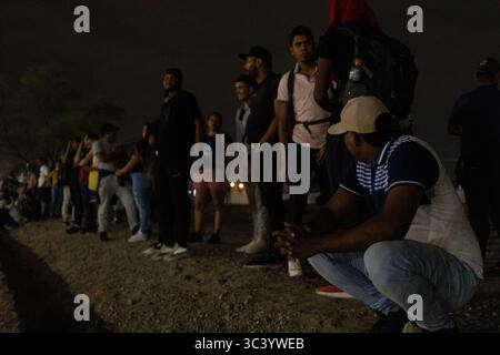 I migranti si riuniscono di notte al confine di Ciudad Juarez, condividendo storie e speranze. Foto Stock