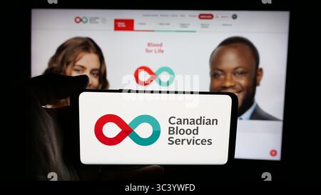 Stoccarda, Germania - 06-09-2025: Persona che tiene il cellulare con il logo dell'organizzazione sanitaria Canadian Blood Services sullo schermo davanti alla pagina web. Foto Stock