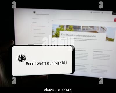 Stoccarda, Germania - 06-11-2025: Persona con smartphone con logo del tribunale Bundesverfassungsgericht (BVerfG) sullo schermo di fronte al sito web. Foto Stock