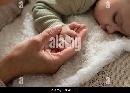 Madre e figlia che si tengono per mano mentre dormono nel letto con una morbida coperta e una copertura a maglia Foto Stock