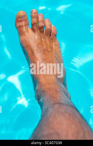 Bellissimi piedi con 30 centimetri di bianco uomo caucasico all'interno di acqua blu e piscina Foto Stock