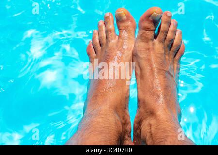 Bellissimi piedi con 30 centimetri di bianco uomo caucasico all'interno di acqua blu e piscina Foto Stock