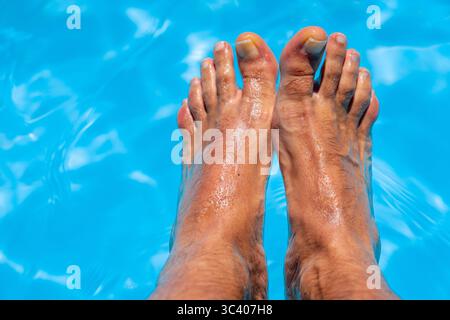 Bellissimi piedi con 30 centimetri di bianco uomo caucasico all'interno di acqua blu e piscina Foto Stock