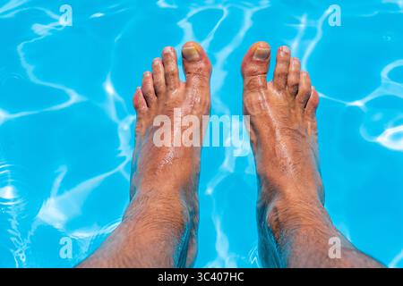 Bellissimi piedi con 30 centimetri di bianco uomo caucasico all'interno di acqua blu e piscina Foto Stock