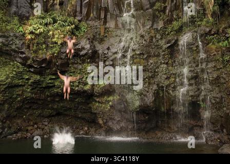 Uomo che salta dalla cascata, Hana, Maui, Hawaii (movimento sfocato e composito digitale). Foto Stock