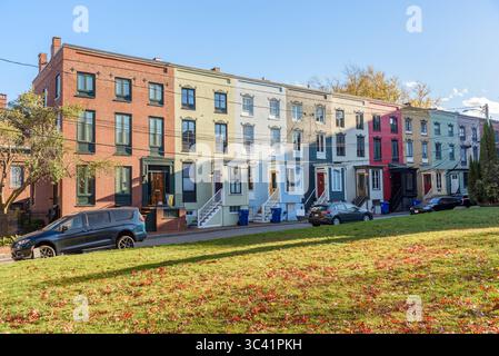 Fila di case cittadine dai colori pastello con scale che conducono alle porte d'ingresso lungo una strada in una soleggiata giornata autunnale Foto Stock