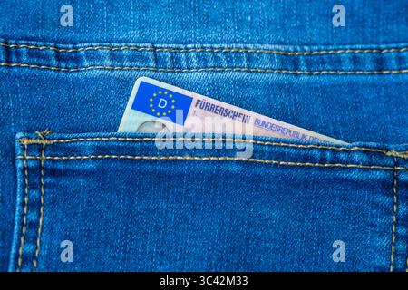 Patente di guida tedesca in tasca per jeans con bandiera UE visibile, patente di guida europea moderna, diritti di trasporto, viaggio dei cittadini dell'UE, documento di mobilità, Foto Stock
