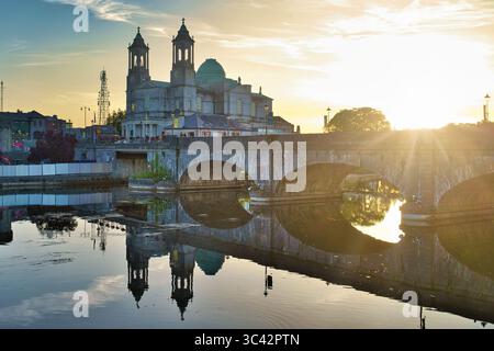 Vista pittoresca di una cattedrale riflessa sull'acqua durante l'ora d'oro in Irlanda. Foto Stock