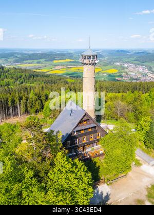 La vista aerea cattura la torre di osservazione di Svatobor circondata da vegetazione lussureggiante, con vasti campi e montagne sullo sfondo. Natura e architettura si fondono splendidamente nella campagna ceca. Foto Stock