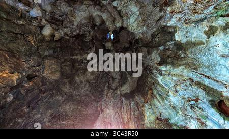 La scena fotografica mozzafiato al tramonto si svolge alle grotte di Batu in Malesia, dove un cielo d'ora d'oro incontra le luci della torre urbana e l'illuminazione notturna della strada. Da Foto Stock