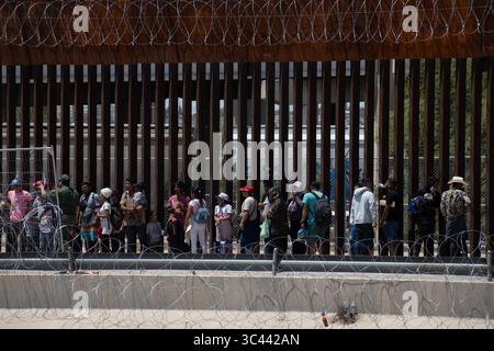 I migranti si riuniscono al confine fortificato di Ciudad Juarez sotto stretta sicurezza. Foto Stock