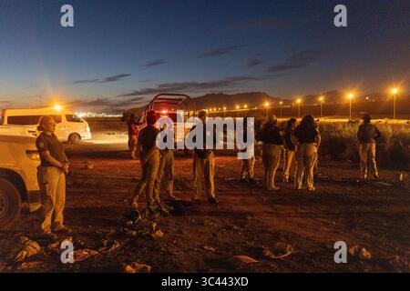 Agenti di pattuglia di frontiera monitorano il confine illuminato di Ciudad Juarez di notte, supervisionando le attività migratorie. Foto Stock