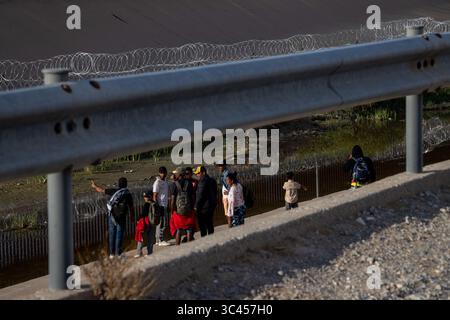 I migranti si riuniscono al recinto di confine di Ciudad Juarez vicino all'acqua. Foto Stock