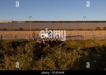 I migranti si radunano presso la torreggiante recinzione di confine a Ciudad Juarez al tramonto. Foto Stock