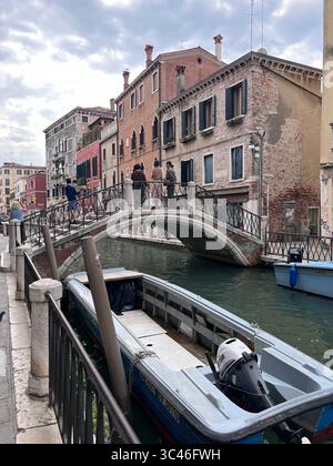 Una mattinata tranquilla a Venezia, con morbide increspature che danzano lungo antiche mura e balconi illuminati dal sole. Foto Stock