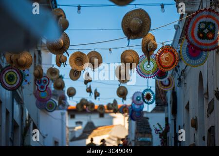 Strada decorata con cappelli appesi ad Alberobello, Puglia, Italia Foto Stock