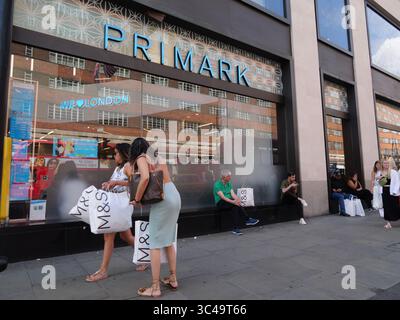 Gli acquirenti fuori dal negozio Primark a Oxford Street, Londra, Regno Unito, portano marchi e borse Spencer durante le vacanze estive Foto Stock