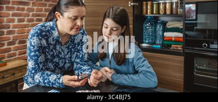 Striscione di famiglia in cucina che ascolta la radio alimentata a batteria in caso di calamità naturali o interruzioni di corrente Foto Stock