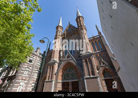 Una grandiosa chiesa in mattoni rossi 'De Gouwekerk' con due torreggianti guglie e un'architettura neogotica ornata si erge maestosamente su un blu brillante Foto Stock