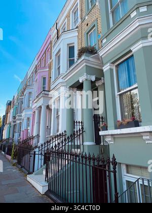 Case colorate fiancheggiano una strada soleggiata a Notting Hill, Londra, che mostra l'architettura iconica e il vibrante fascino estivo in questo famoso quartiere. Foto Stock