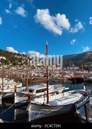 Barche da pesca tradizionali ancorate nel porto turistico di Port de Sòller, Maiorca, Spagna, con un cielo blu brillante e piccole nuvole sparse in un giorno d'estate Foto Stock