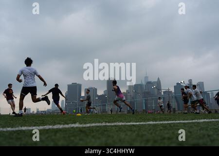 New York, USA. 27 luglio 2025. Le persone giocano a rugby nel clima nebbioso al Brooklyn Bridge Park il 27 luglio 2025 a New York. Un avviso sulla qualità dell'aria è stato pubblicato per New York City e le sue aree circostanti a causa del fumo provocato dagli incendi in Canada. Credito: Liao Pan/China News Service/Alamy Live News Foto Stock