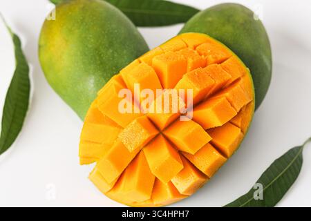Primo piano di un succoso mango maturo tagliato a fettine con un motivo a griglia e parzialmente girato all'interno verso l'esterno, rivelando una polpa arancione. Presentato su sfondo bianco. Foto Stock