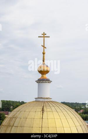 Chiesa del Profeta Elia, Torzhok, Russia. Foto verticale che mostra una cupola dorata della chiesa coronata da una croce sotto il cielo nuvoloso in una simbiosi diurna Foto Stock