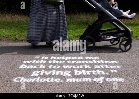 EMBARGO AL 0001 MERCOLEDÌ 30 LUGLIO SOLO USO EDITORIALE Vista generale di un genitore e un bambino, al Wimbledon Park di Londra, come parte della campagna positive Steps di BACP, dove storie personali sono dipinte lungo un percorso per evidenziare come la terapia ha aiutato le nuove mamme. Data di pubblicazione: Mercoledì 30 luglio 2025. Foto Stock