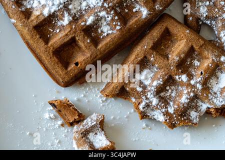 Cialde di pasta al cioccolato belga cosparse di zucchero a velo su sfondo bianco. Vista dall'alto. Primo piano. Foto di alta qualità Foto Stock