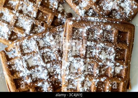 Cialde di pasta al cioccolato belga cosparse di zucchero a velo su sfondo bianco. Vista dall'alto. Primo piano. Foto di alta qualità Foto Stock