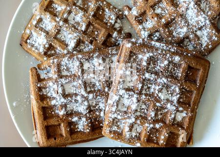 Cialde di pasta al cioccolato belga cosparse di zucchero a velo su sfondo bianco. Vista dall'alto. Primo piano. Foto di alta qualità Foto Stock