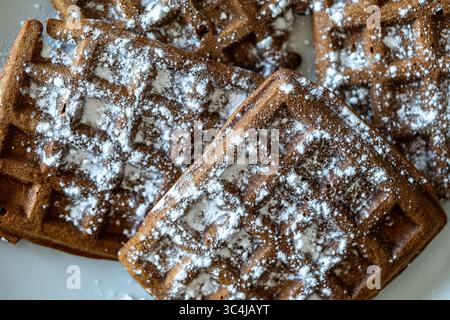 Cialde di pasta al cioccolato belga cosparse di zucchero a velo su sfondo bianco. Vista dall'alto. Primo piano. Foto di alta qualità Foto Stock