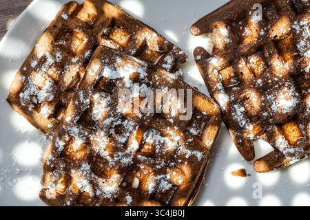 Cialde di pasta al cioccolato belga cosparse di zucchero a velo su sfondo bianco. Vista dall'alto. Primo piano. Foto di alta qualità Foto Stock