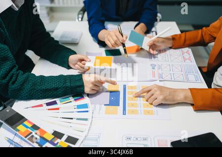 Vista ravvicinata del team di sviluppatori dell'interfaccia utente che ha avviato un brainstorming sul proprio progetto con laptop, smartphone e tablet digitale. Agenzia di sviluppo digitale creativo. Foto Stock