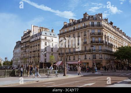 Vista sulla strada di Rue de la Cité a Parigi con i classici edifici Haussmann, persone che camminano e attraversano la strada in una giornata di sole. Atmosfera urbana nel Foto Stock