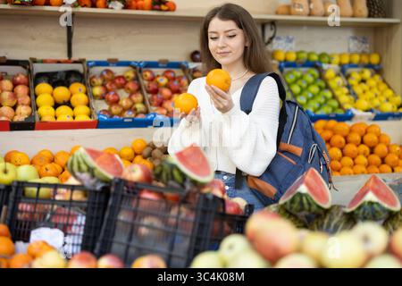 Comprare frutta al supermercato - la ragazza sceglie le arance Foto Stock