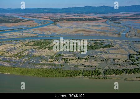 Veduta aerea dei tortuosi corsi d'acqua si intagliano attraverso il paesaggio, riflettendo il cielo, mentre la vegetazione lussureggiante contrasta con i campi aperti, Teknaf e Chit Foto Stock