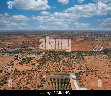 Veduta aerea paesaggio africano cespuglio e fattorie villaggio sullo sfondo, nuovi sviluppi nel paese , giorno di sole diurno con soffici nuvole Foto Stock