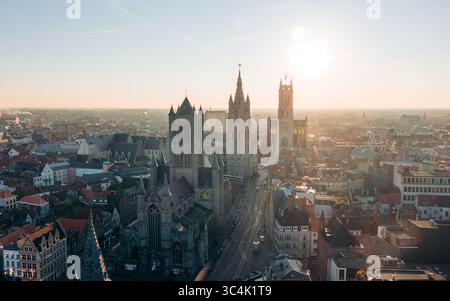 Vista aerea della luce del sole che baciano le guglie della Chiesa di San Nicola e del Belfry di Gand, che sfoggiano sfumature dorate nella città storica, Gent, Fiandre, Belgio. Foto Stock