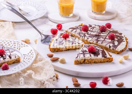 Torta di carote piatta fatta in casa con noci, ghiacciata con formaggio spalmabile e succo di carota Foto Stock