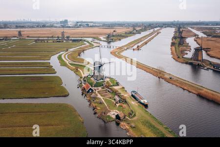 Vista aerea degli storici mulini a vento che si innalzano fieri accanto ai tranquilli canali, riflettendo il cielo coperto a Kinderdijk, Olanda meridionale, Paesi Bassi. Foto Stock