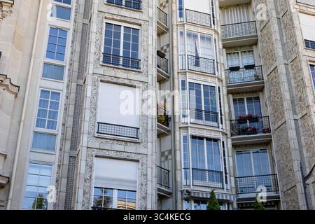 Elegante facciata parigina dell'edificio di appartamenti, dettagliati lavori in pietra, balconi ornati e grandi finestre. Ideale per immobili, viaggi e architetture Foto Stock