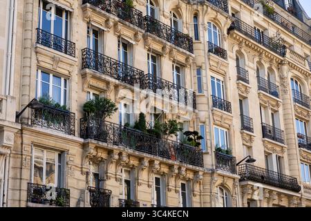 Elegante facciata parigina dell'edificio di appartamenti, con balconi ornati in ferro battuto e finestre illuminate dal sole. Ideale per viaggi, immobili e architetti Foto Stock