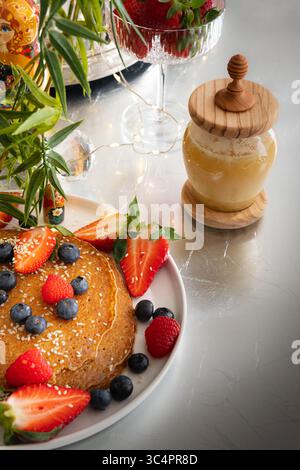 Pancake con fragole, lamponi, mirtilli e miele Foto Stock