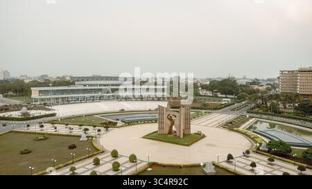 Vista aerea del Monument de l'Indépendance in piedi con orgoglio tra prati curati e piscine riflettenti, in contrasto con lo skyline della città, Lomé, la regione marittima e il Togo. Foto Stock