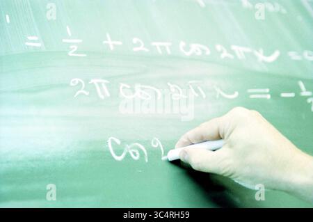 Esami, matematica, 15-05-2000 Whizgle News, Dutch Desk, Paesi Bassi, 1950-2000 Una mano scrive equazioni matematiche su una lavagna verde, con simboli e formule che includono frazioni e funzioni trigonometriche. Foto Stock