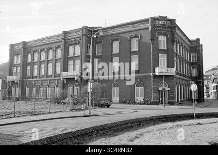 Grande edificio alla fine di Julianaweg a Wijk aan Zee, Wijk aan Zee, Julianaweg, 09-02-1979 Whizgle News, Dutch Desk, i Paesi Bassi, 1950-2000 Un grande edificio storico in mattoni con finestre multiple e balconi, adagiato su una strada curva. Davanti, le biciclette sono parcheggiate e un veicolo è posizionato nelle vicinanze, mentre una recinzione segna il perimetro della proprietà. L'architettura della struttura mette in mostra dettagli ornamentali che riflettono il suo passato. Foto Stock
